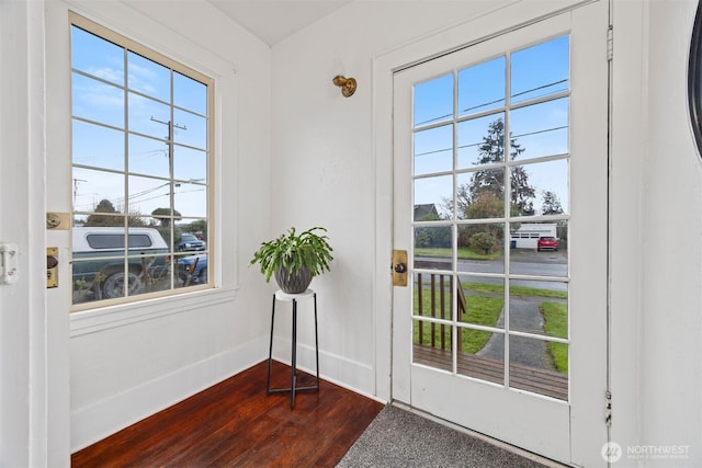 doorway with a healthy amount of sunlight, baseboards, and dark wood-type flooring