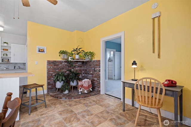 interior space featuring ceiling fan, a fireplace, and baseboards