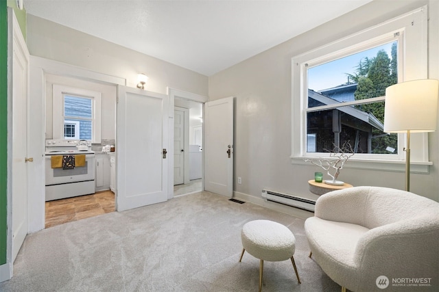 sitting room featuring light carpet, a baseboard radiator, and a wealth of natural light