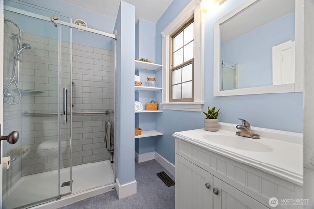 bathroom featuring visible vents, baseboards, a shower stall, and vanity