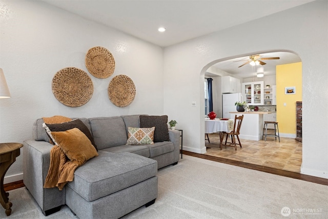 living room with baseboards, arched walkways, ceiling fan, light wood-type flooring, and recessed lighting