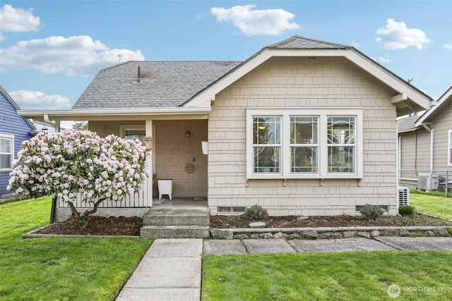 view of front of property with a shingled roof and a front yard