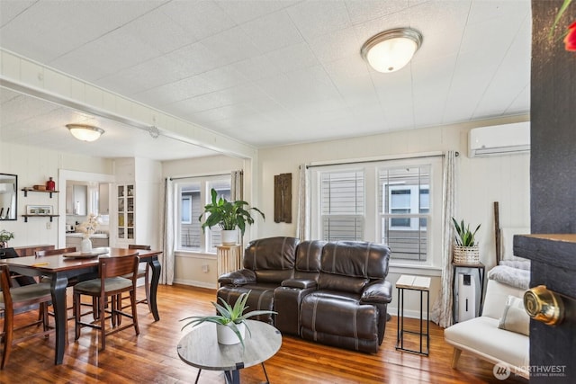 living area with a wall mounted air conditioner and wood finished floors