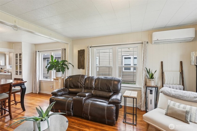 living room featuring plenty of natural light, a wall mounted AC, and wood finished floors