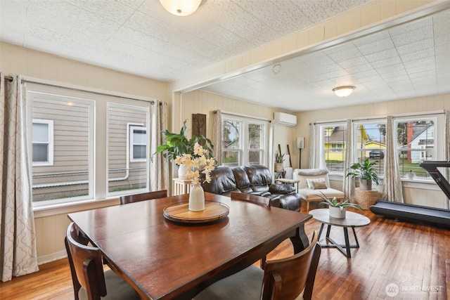 dining space featuring a wall mounted air conditioner and hardwood / wood-style floors