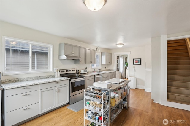 kitchen featuring under cabinet range hood, gray cabinetry, stainless steel appliances, and light wood-style floors