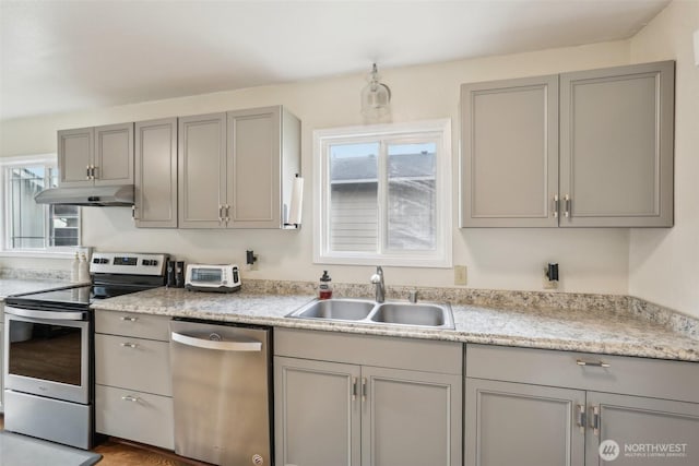 kitchen featuring under cabinet range hood, gray cabinets, appliances with stainless steel finishes, and a sink