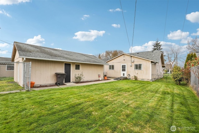 back of property featuring a yard, roof with shingles, and fence