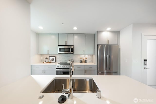 kitchen with light countertops, appliances with stainless steel finishes, gray cabinets, and backsplash