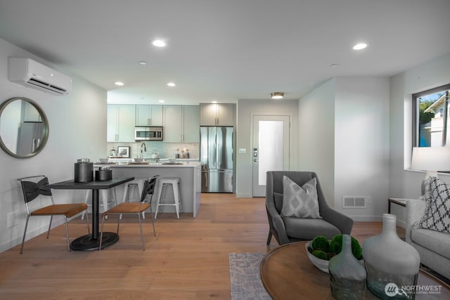 kitchen featuring appliances with stainless steel finishes, an AC wall unit, backsplash, and open floor plan