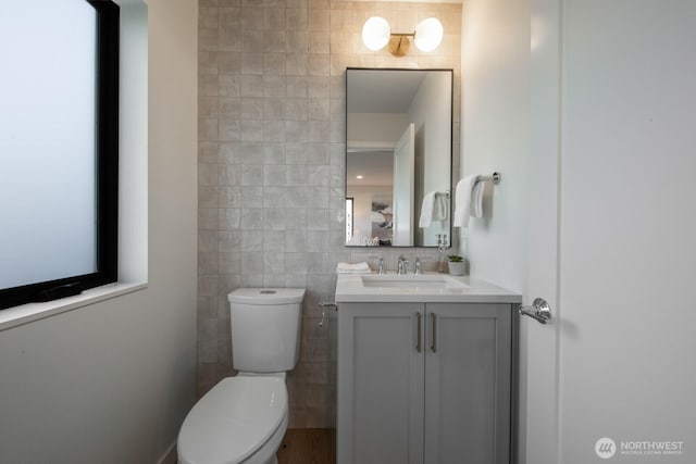 bathroom with tile walls, toilet, and vanity