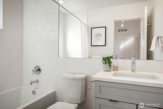 bathroom featuring toilet, tile walls, vanity, visible vents, and shower / bathtub combination with curtain