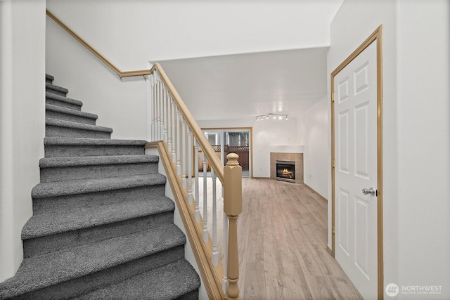 stairs with wood finished floors and a tile fireplace