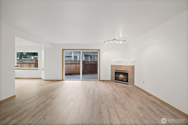 unfurnished living room featuring baseboards, a fireplace, and light wood finished floors