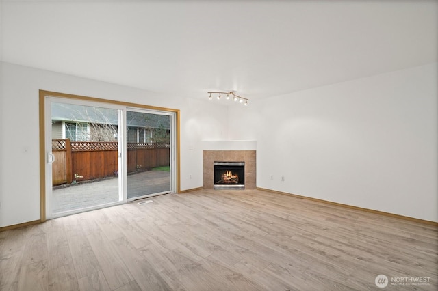 unfurnished living room with a fireplace, visible vents, wood finished floors, and baseboards