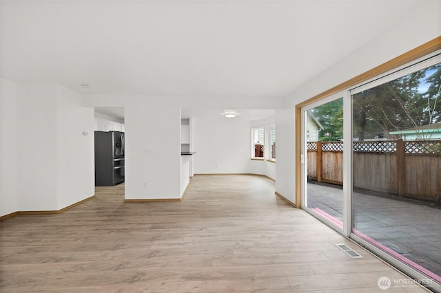 unfurnished room with light wood-type flooring, baseboards, and visible vents