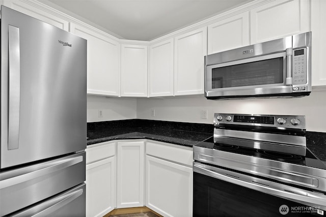 kitchen with dark stone counters, white cabinets, and appliances with stainless steel finishes