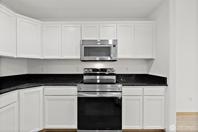 kitchen with white cabinets, stainless steel appliances, and dark stone countertops