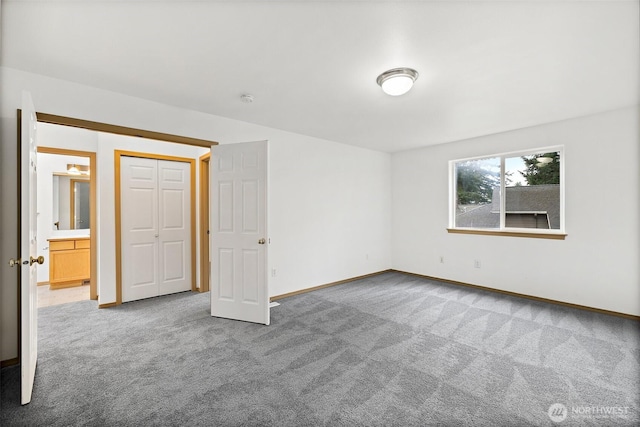 unfurnished bedroom featuring baseboards, carpet floors, and ensuite bath