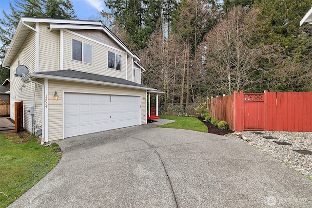 view of side of property with driveway, a garage, and fence