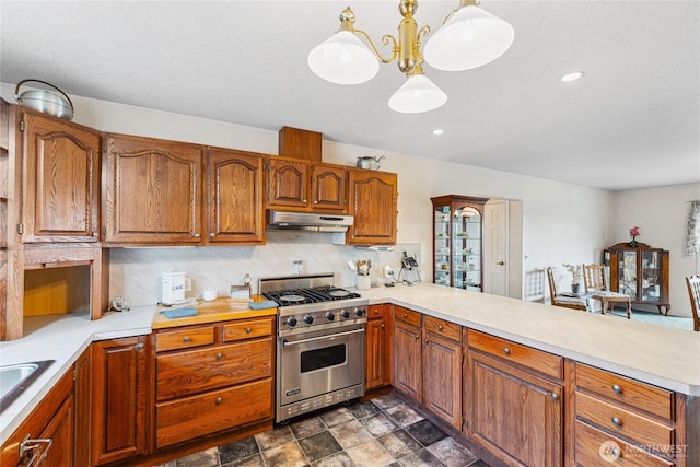 kitchen with a peninsula, under cabinet range hood, light countertops, and luxury stove