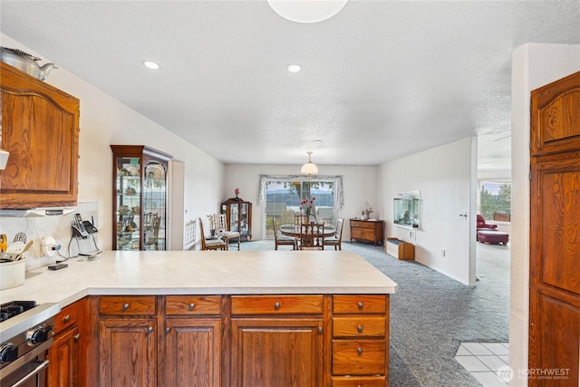 kitchen featuring carpet floors, light countertops, open floor plan, stainless steel range with gas stovetop, and a peninsula