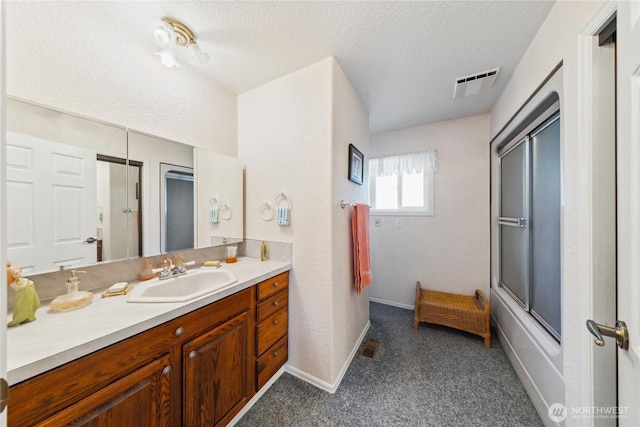 bathroom featuring visible vents, enclosed tub / shower combo, a textured ceiling, vanity, and baseboards