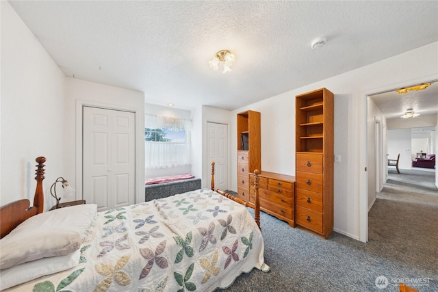 carpeted bedroom with multiple closets and a textured ceiling