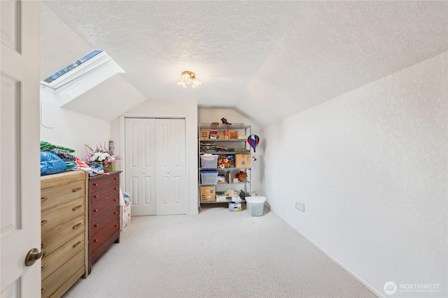 additional living space with light carpet, lofted ceiling with skylight, and a textured ceiling