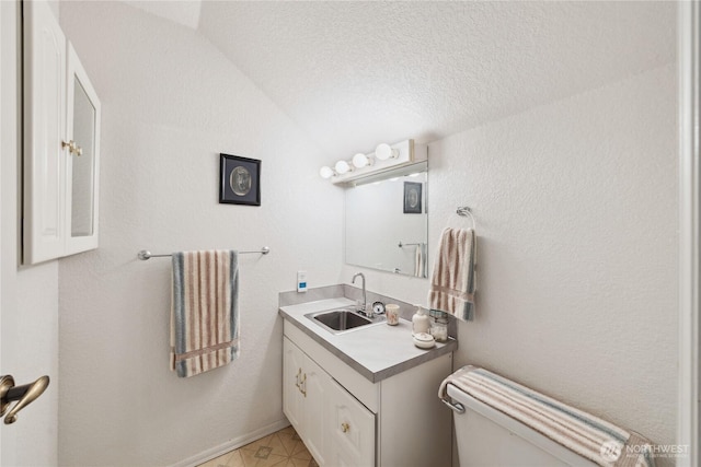 half bath with toilet, lofted ceiling, a textured ceiling, and vanity