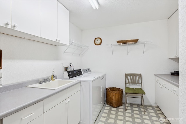 laundry area with cabinet space, light floors, a sink, and washing machine and clothes dryer