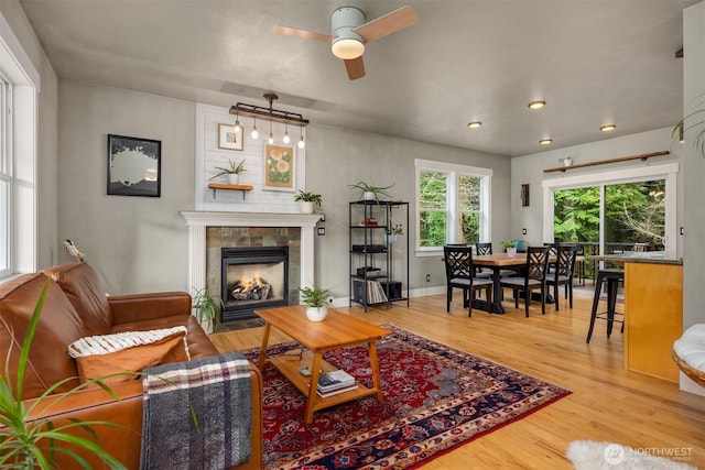 living room with recessed lighting, a fireplace, wood finished floors, a ceiling fan, and baseboards