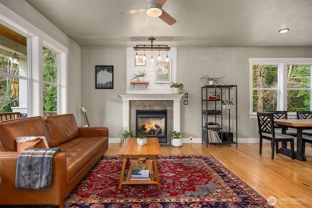 living room with ceiling fan, baseboards, wood finished floors, and a tile fireplace