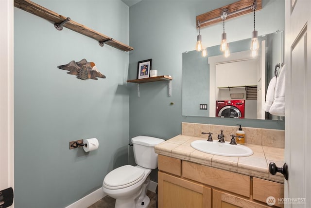 bathroom with toilet, washer / dryer, baseboards, and vanity