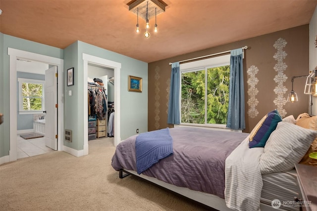 bedroom with carpet, a walk in closet, multiple windows, and baseboards