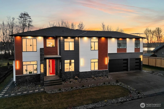 modern home with a garage, driveway, and fence