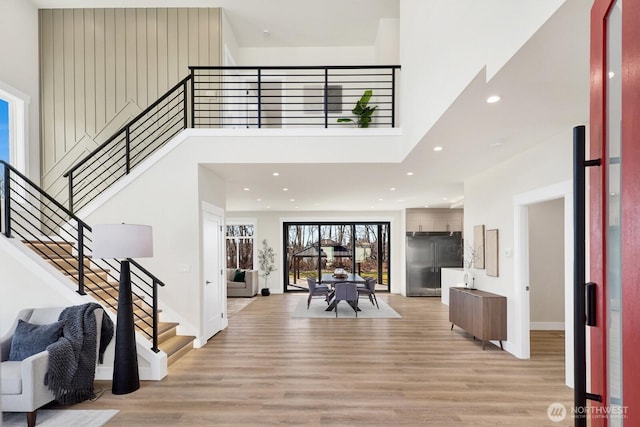 entrance foyer with light wood-type flooring, a high ceiling, stairway, and recessed lighting