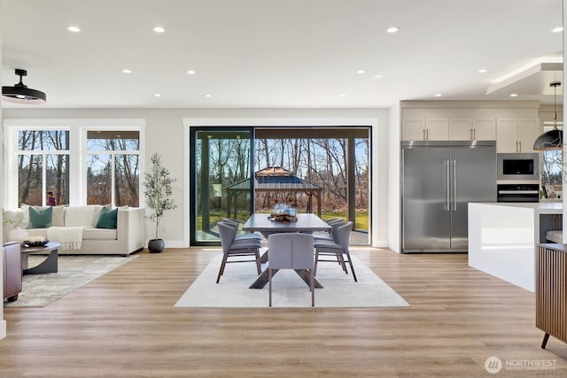 dining space featuring baseboards, light wood finished floors, and recessed lighting