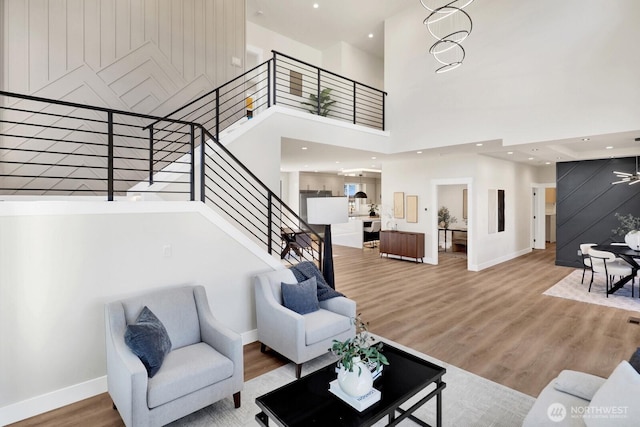 living area with recessed lighting, wood finished floors, a towering ceiling, baseboards, and stairway