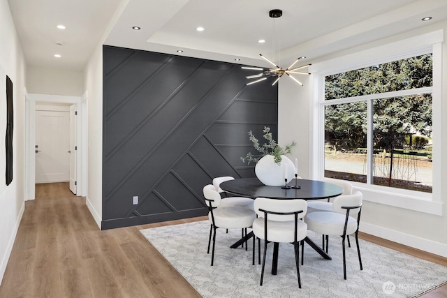 dining room featuring baseboards, a decorative wall, wood finished floors, and recessed lighting