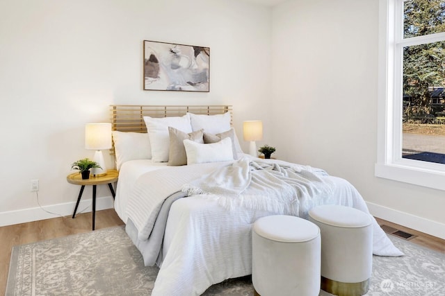 bedroom featuring wood finished floors, visible vents, and baseboards