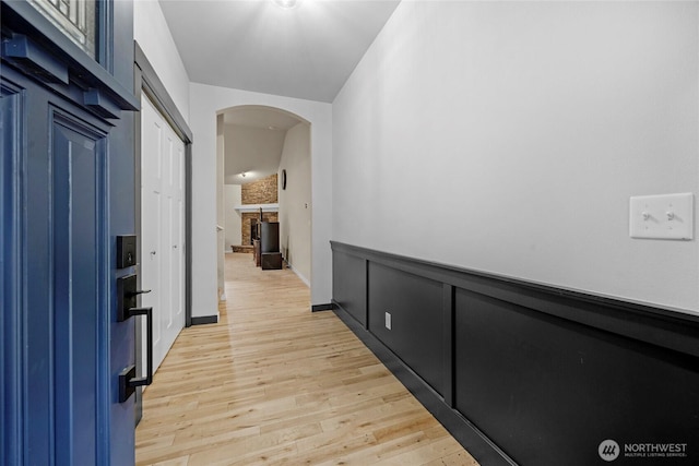 hallway featuring arched walkways and light wood-style floors