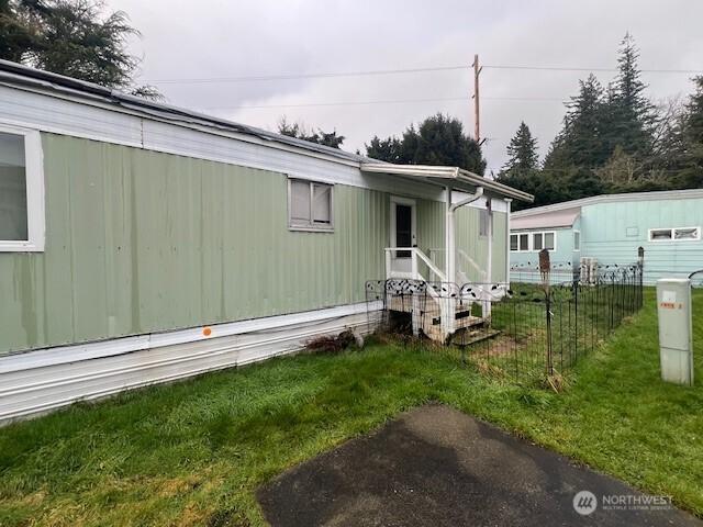 view of side of home featuring a lawn and fence