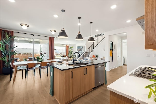 kitchen featuring appliances with stainless steel finishes, light wood-type flooring, a sink, and a kitchen island with sink