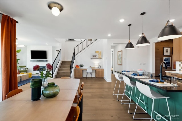 dining room with recessed lighting, dark wood-style flooring, and stairway