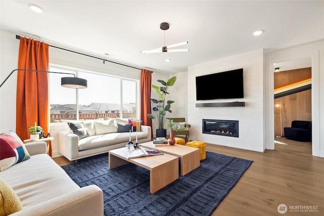 living area with a glass covered fireplace, wood finished floors, and recessed lighting