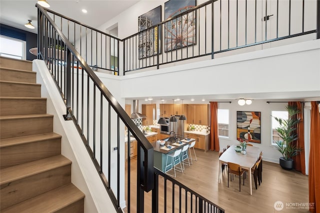 staircase with recessed lighting, a high ceiling, and wood finished floors