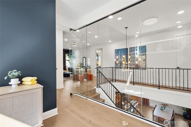 hallway featuring baseboards, wood finished floors, an inviting chandelier, an upstairs landing, and recessed lighting