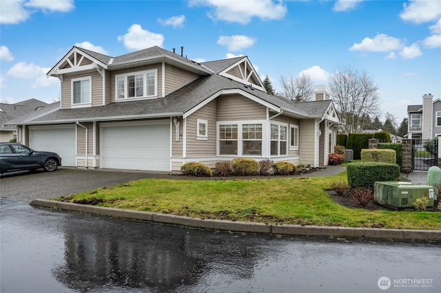 view of front of property featuring driveway, an attached garage, a front lawn, and a shingled roof