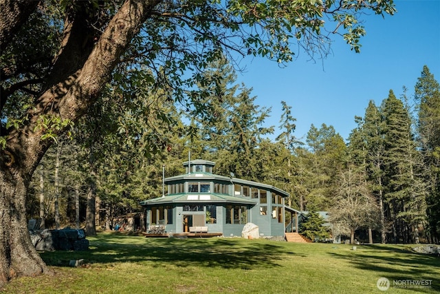 view of front of house featuring a forest view and a front lawn